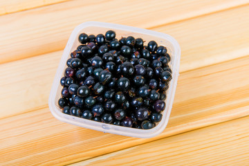Black currant in a transparent plastic box. Useful fruit for a healthy diet

