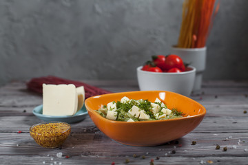 pasta green with spinach and mozzarella cheese and greens in an orange bowl, French mustard,...