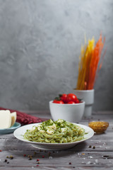 pasta green with spinach and mozzarella cheese and greens in a white plate, French mustard, colored...