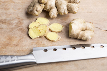 Fototapeta premium Ginger next to kitchen knife on wood. Food
