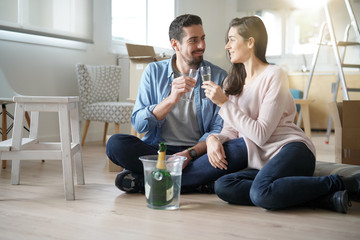 Couple cheering with champagne in new home