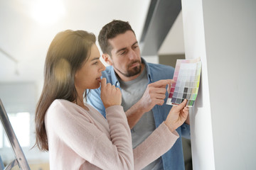 Couple looking at colour sample to renovate home interior - obrazy, fototapety, plakaty