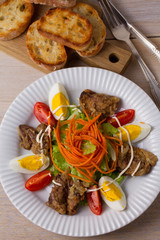 Chicken liver, carrot, eggs, tomatoes, lettuce and fried onion salad. Liver and vegetables. Top, overhead, above view, vertical