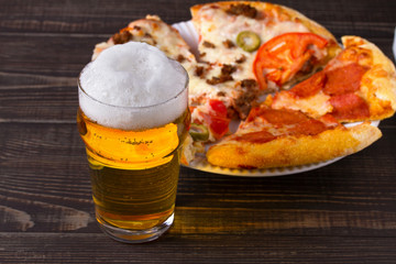 Beer and pizza on dark wooden background. Ale and food, horizontal