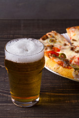 Beer and pizza on dark wooden background. Ale and food, vertical