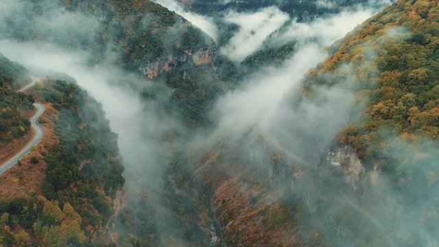 Aerial pass inside a deep gorge/canyon of a national park in Greece during autumn/winter while fog slowly kicks in. 