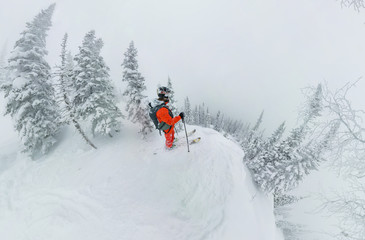 Fototapeta na wymiar Man skier freerider standing at top of ridge, adventure winter freeride extreme sport