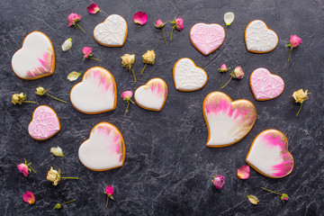 st valentines day arrangement of glazed heart shaped cookies and decorative flowers on dark tabletop