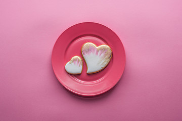 top view of sweet glazed cookies on plate isolated on pink, st valentines day holiday concept