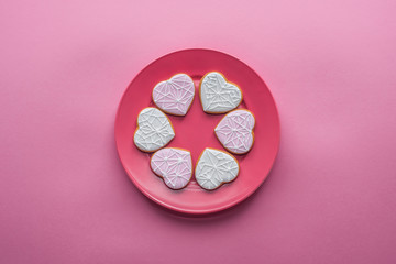 top view of sweet glazed cookies on plate isolated on pink, st valentines day holiday concept