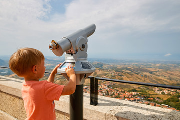 little boy looking through sightseeing binoculars on San Marino.
