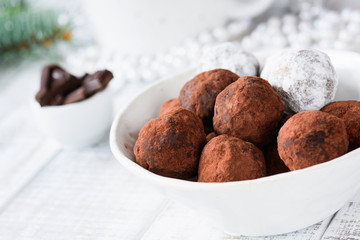 Raw vegan chocolate truffles made with dates and raw chocolate in white bowl. Horizontal view, closeup