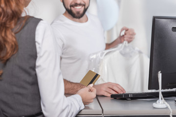 cropped shot of woman giving credit card to dry cleaning manager