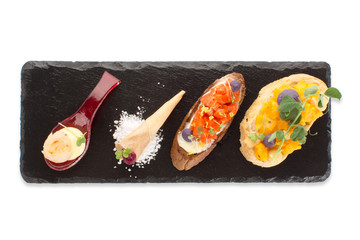 Assortment of snacks with a beautiful serving on an isolated board, top view