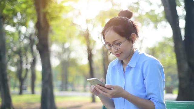 Asian Woman is using smartphone in the park.