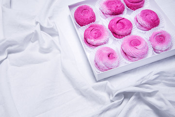 Homemade pink marshmallows. zephyr on white textille background.