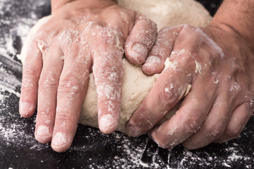 Fototapeta premium Male hands kneading dough, baking preparation closeup.