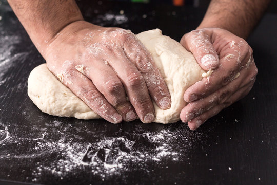 Male hands kneading dough, baking preparation closeup.