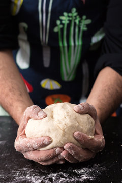 Male hands  holding ball of dough, baking preparation closeup.