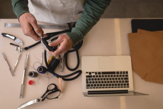 Worker making leather straps in workshop