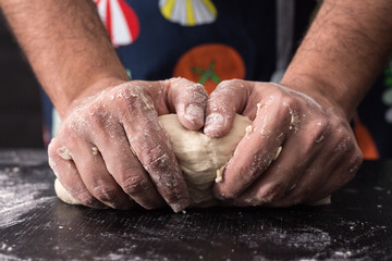 Male hands kneading dough, baking preparation closeup.