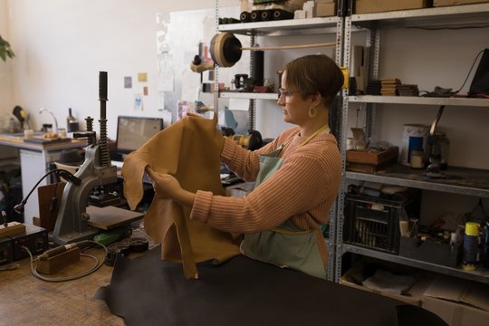 Worker checking leather in workshop
