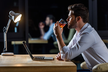 side view of businessman drinking whiskey in the evening