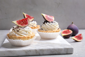 Marble board with tasty cakes on grey table