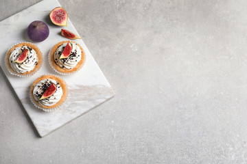 Marble board with tasty cakes on grey table, top view