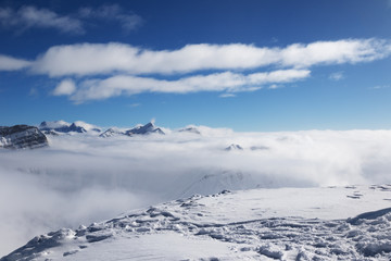 Snowy slope and sunlight mountains under clouds