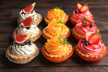 Tasty colorful cakes on wooden background