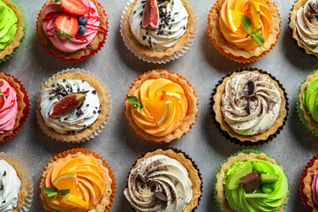 Tasty colorful cakes on grey background, top view
