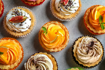 Tasty colorful cakes on grey background, top view
