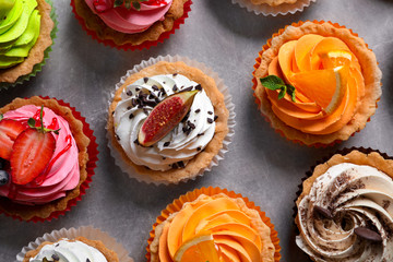 Tasty colorful cakes on grey background, top view