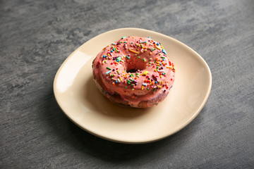 Plate with yummy colorful donut on grey background