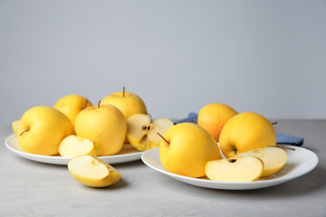 Plates with ripe yellow apples on table