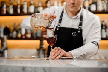 Barman adding alcoholic drink into an elegant glass
