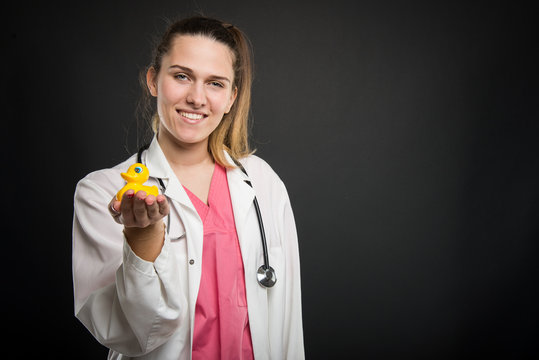 Young attractive pediatrician doctor holding yellow toy duck