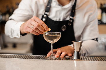 Barman adding a lemon peel into a cocktail glass