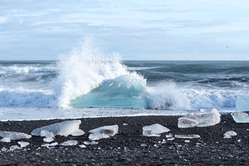 Ice berg with wave on a black beach in Iceland