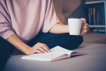 Unrecognizable woman enjoying in coffee time with a book.