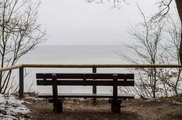 Fototapeta na wymiar Empty bench on the shore of the ocean on a winter day.