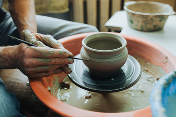 Fototapeta na wymiar Potter hands makes clay pot on the pottery wheel
