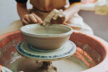 Woman hands makes clay pot on the pottery wheel