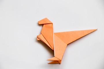 Origami orange paper fold as raptor dinosaur on white background
