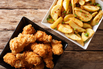 Delicious food: deep-fried chicken wings in breadcrumbs and potato close-up. horizontal top view