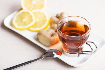 Tea cup with lemon and ginger on white plate. Infusion.