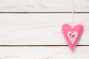 Valentine's Day concept with a pink felt handmade heart against white shabby wooden background, With pleanty of copy space for your text