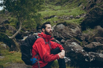 Male hiker sitting on the rock on countryside landscape