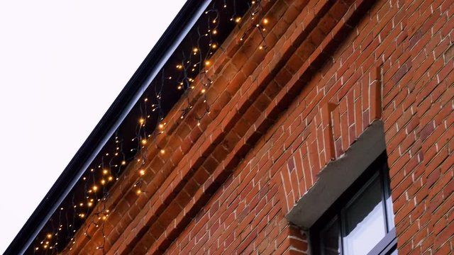 Exterior of the red brick house with garland lights decorations for Christmas or New Year. 4K
